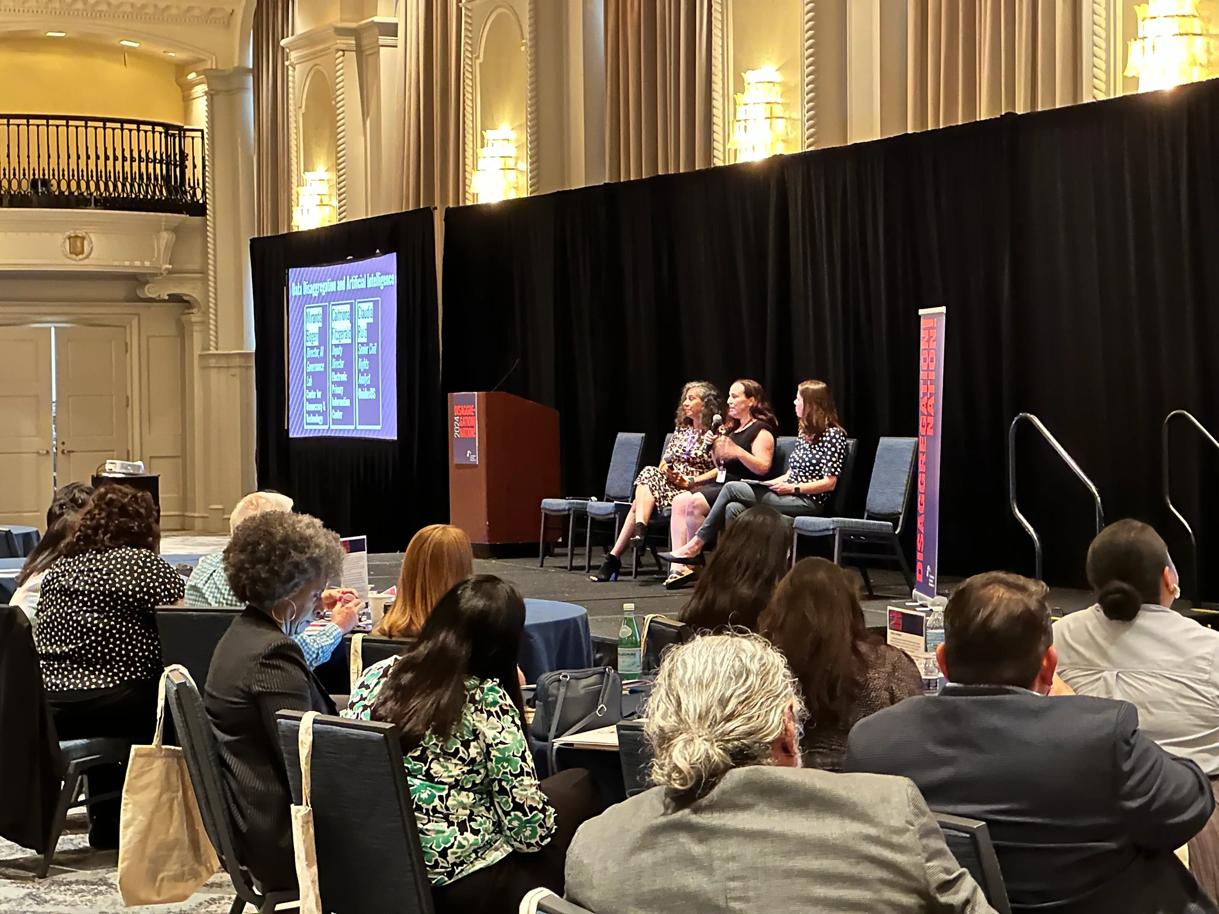 A panel discussion on stage photographed from among the audience